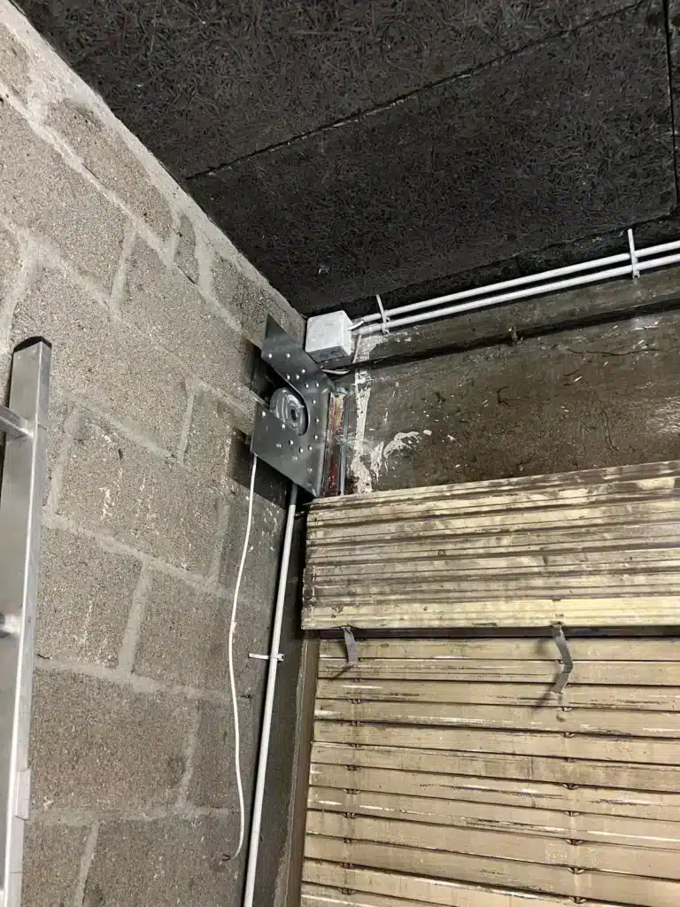 Axe et lames d'un rideau métallique dans le coffre, vue rapprochée en cours d'intervention