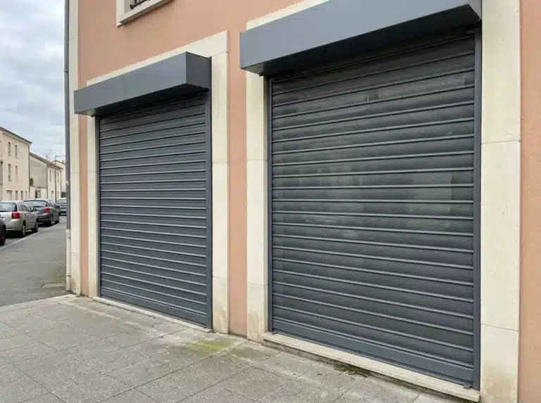 Deux rideaux métalliques fermés, l’un à lames pleines et l’autre microperforé, devant des vitrines voisines.