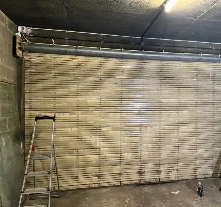 Rideau métallique à lames en cours d'installation dans un local, avec échelles