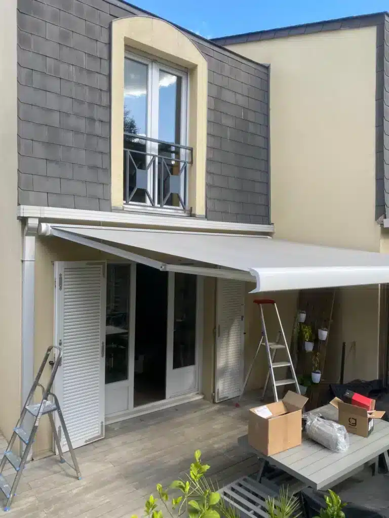 Store banne gris déployé au-dessus d'une porte-fenêtre de maison