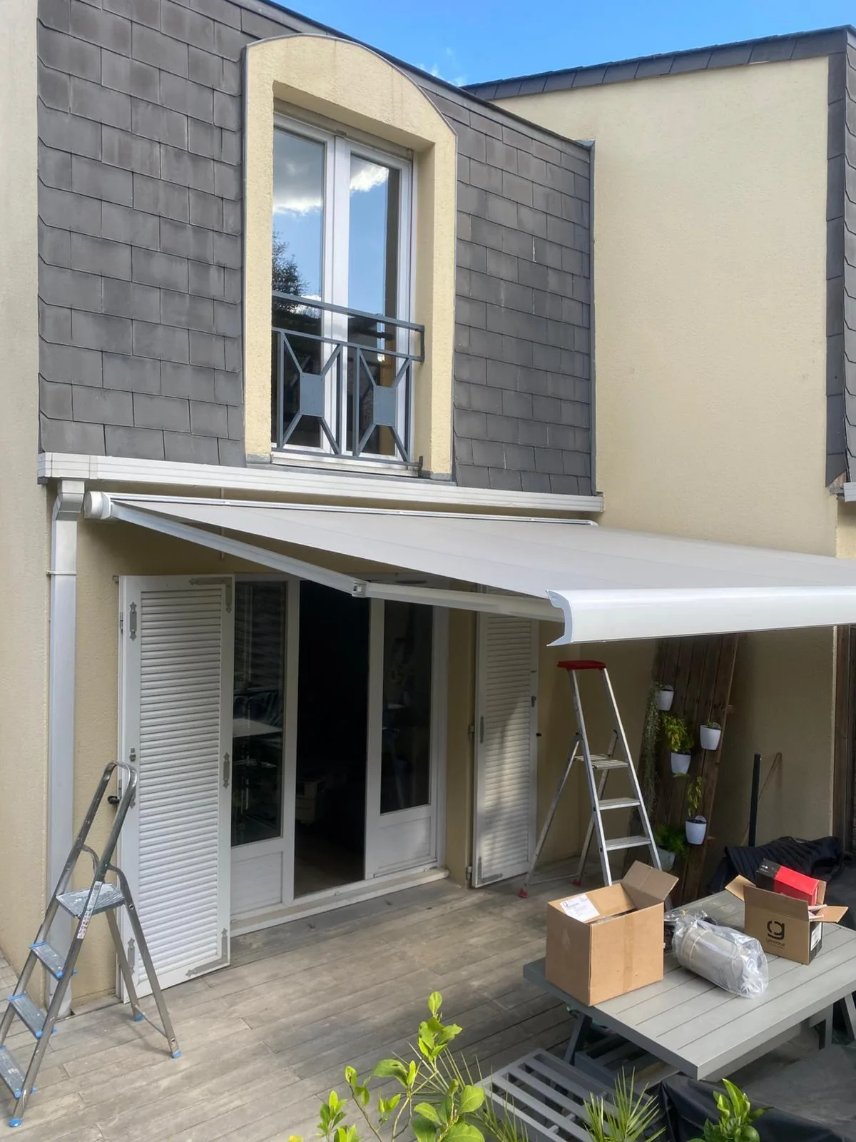 Store banne gris déployé au-dessus d'une porte-fenêtre de maison