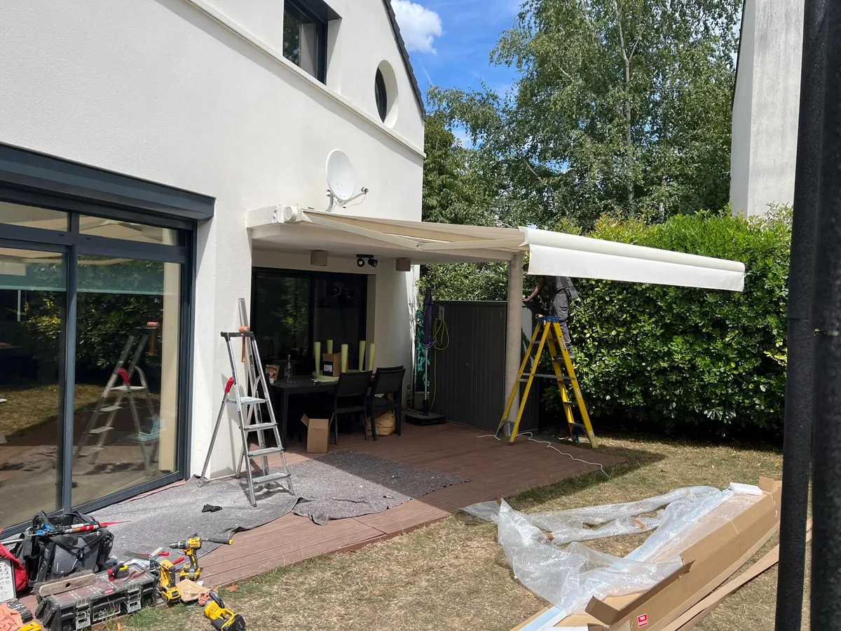 Terrasse de maison avec pergola à toile en cours de pose, outillage au sol