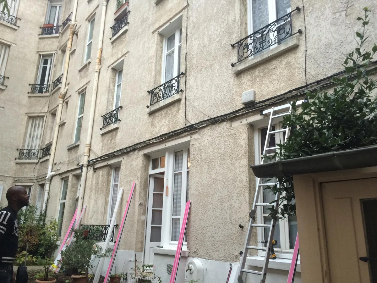 Façade d'immeuble ancien pendant la pose de volets roulants, échelle et étais