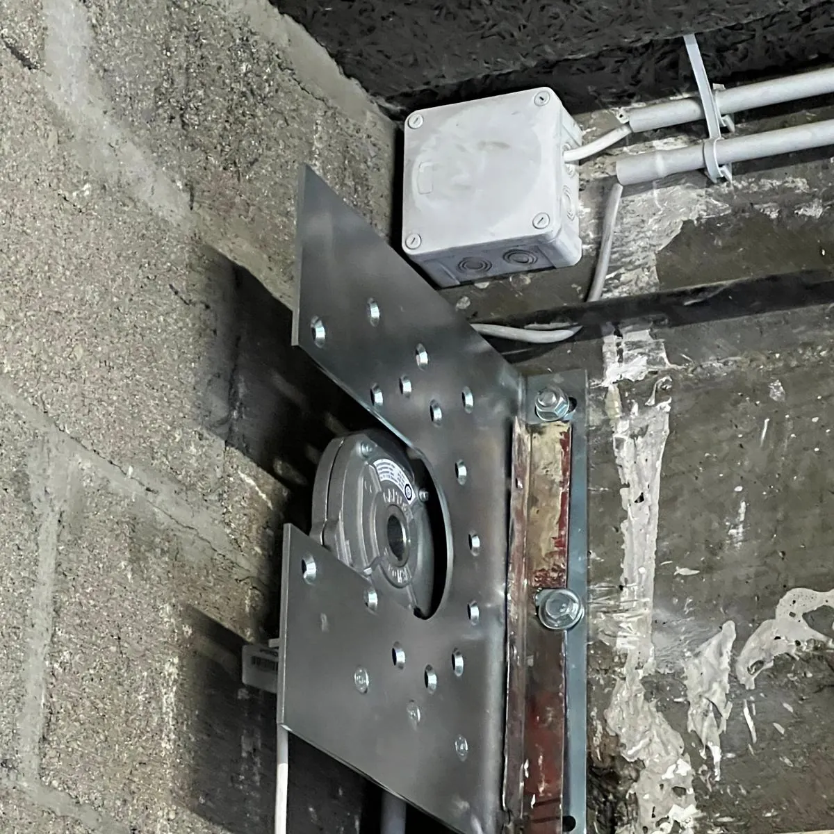 Moteur central fixé au mur à l'extrémité de l'axe d'un rideau métallique