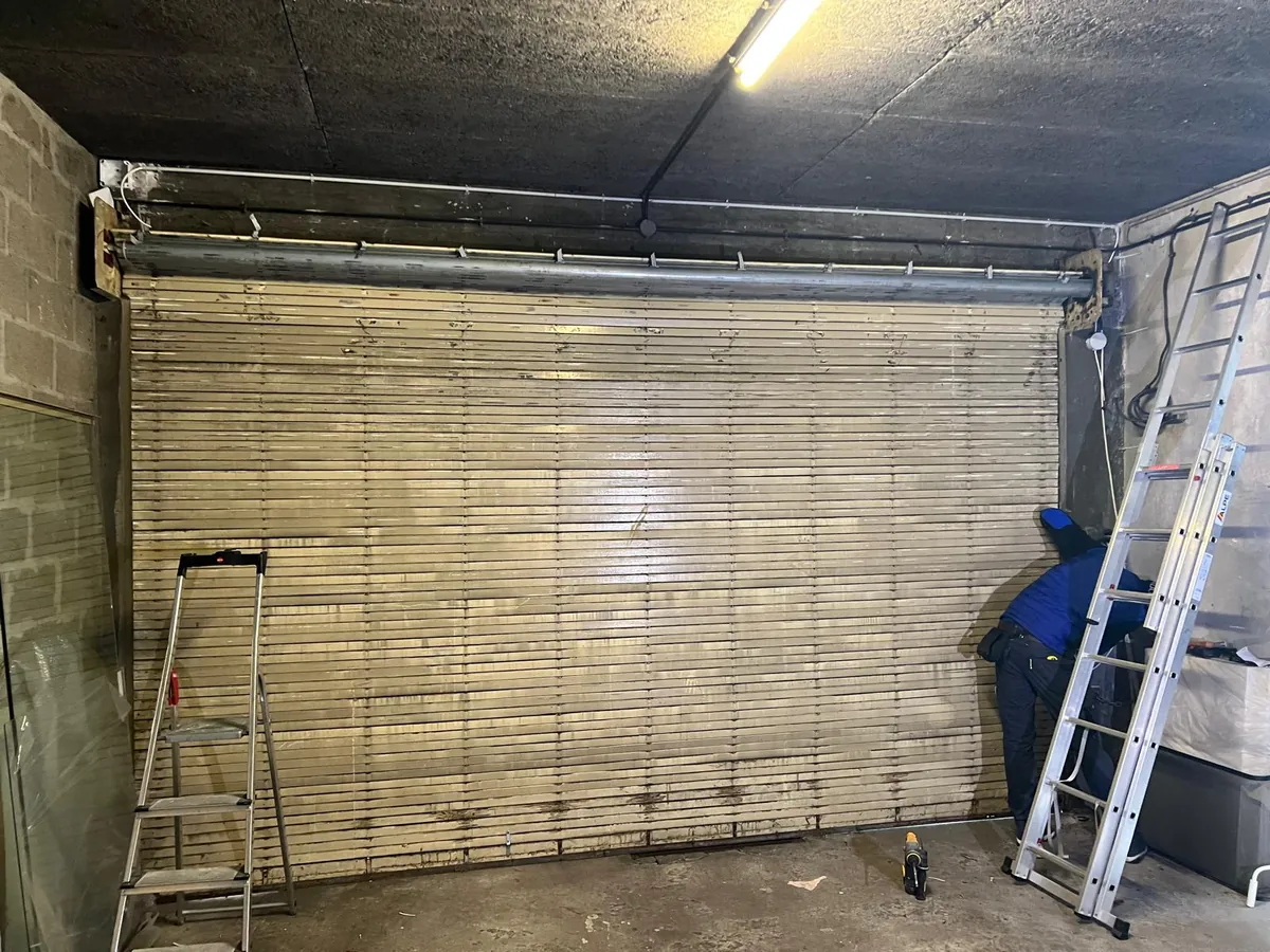 Rideau métallique à lames dans un local, en cours de motorisation