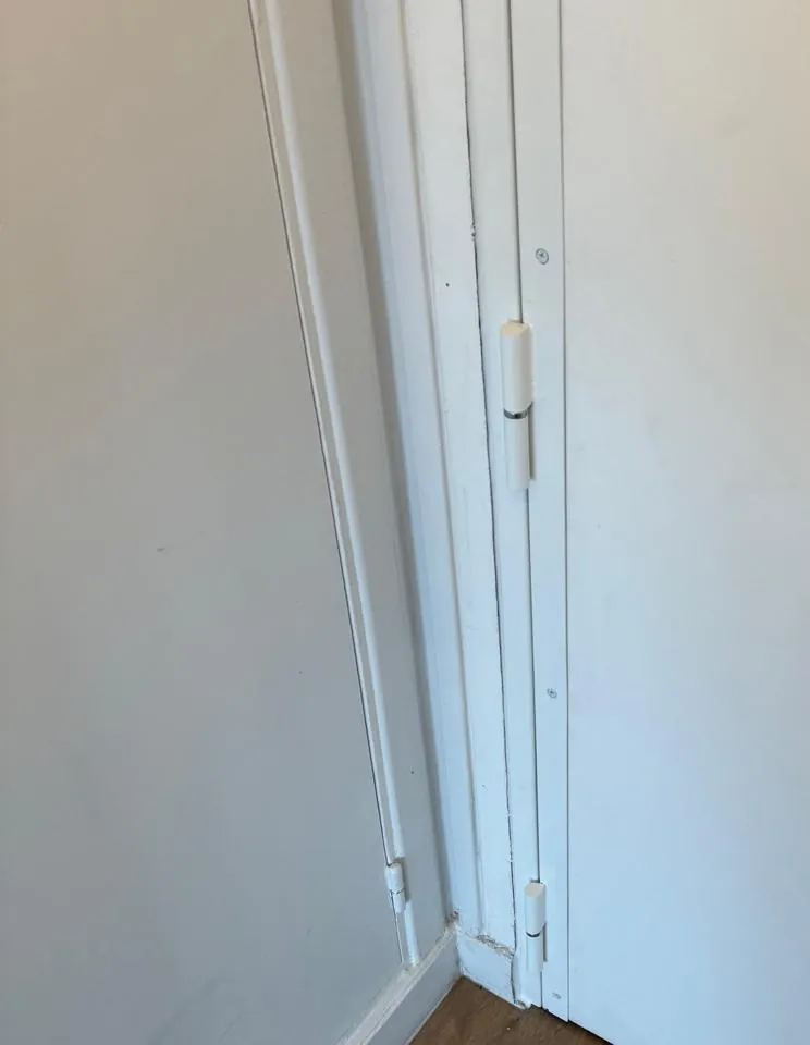 Gros plan du bâti acier et des paumelles d'une porte blindée sur mesure posée
