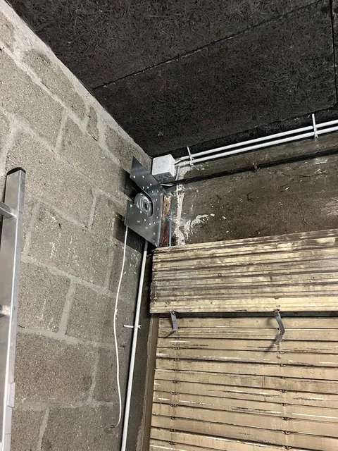 Axe et lames d'un rideau métallique dans le coffre, vue rapprochée en cours d'intervention