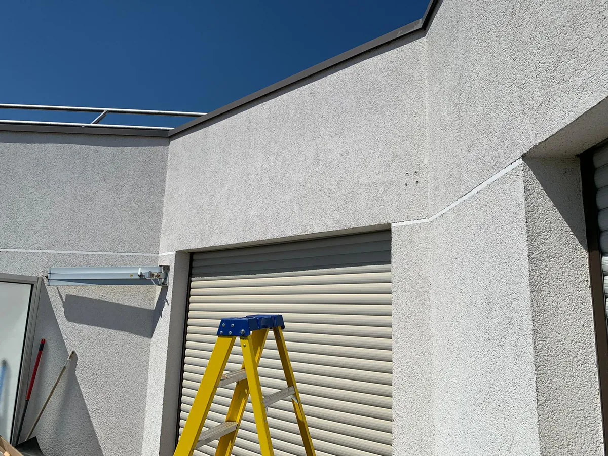 Façade avec coffre de store banne et volet roulant, escabeau jaune, pendant une intervention