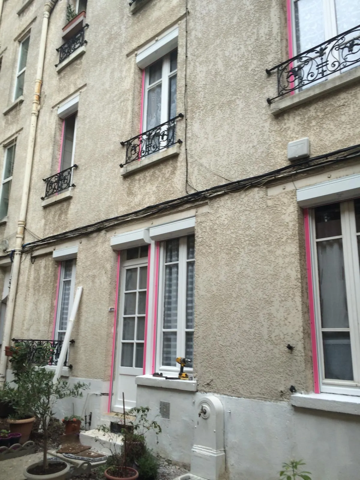 Façade d'immeuble ancien avec balcons en fer forgé, chantier de pose de volets roulants