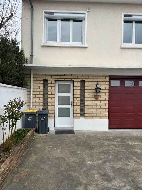 Maison francilienne avec porte d'entrée et porte de garage rouge, vue de la rue