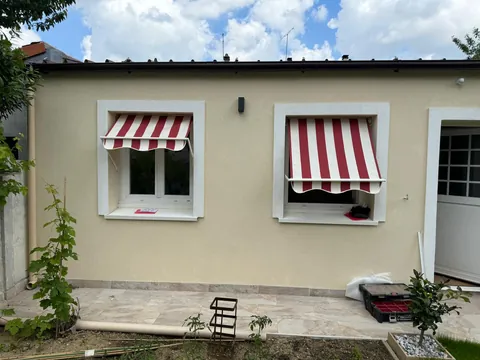 Stores corbeille à toile rayée rouge et blanche posés sur les fenêtres d'une maison