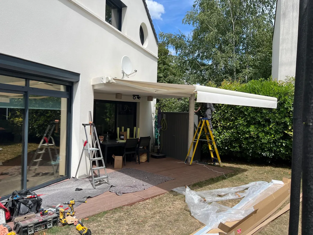 Terrasse de maison avec pergola à toile en cours de pose, outillage au sol