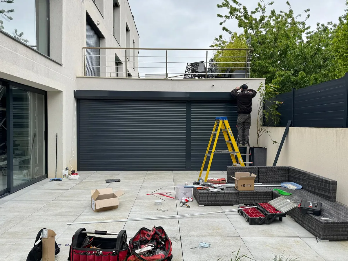 Volet roulant gris anthracite de grande largeur sur une baie de maison moderne, en cours de pose